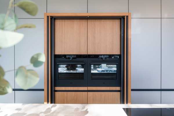 Greeploze keuken met verborgen Hide&Slide kast, afgewerkt in massief gegroefd eiken en bronskleurige matlak