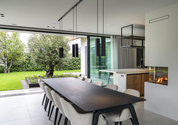 Luxe keuken in notelaar fineer met grote eettafel en veel natuurlijk licht