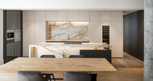 Keuken met groot marmeren keukeneiland en houten eettafel, afgewerkt in eiken fineer
