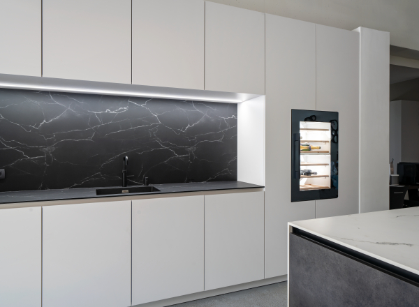 Overzicht van de Champagne Primofiore keuken met witte kasten en zwarte marmeren achterwand